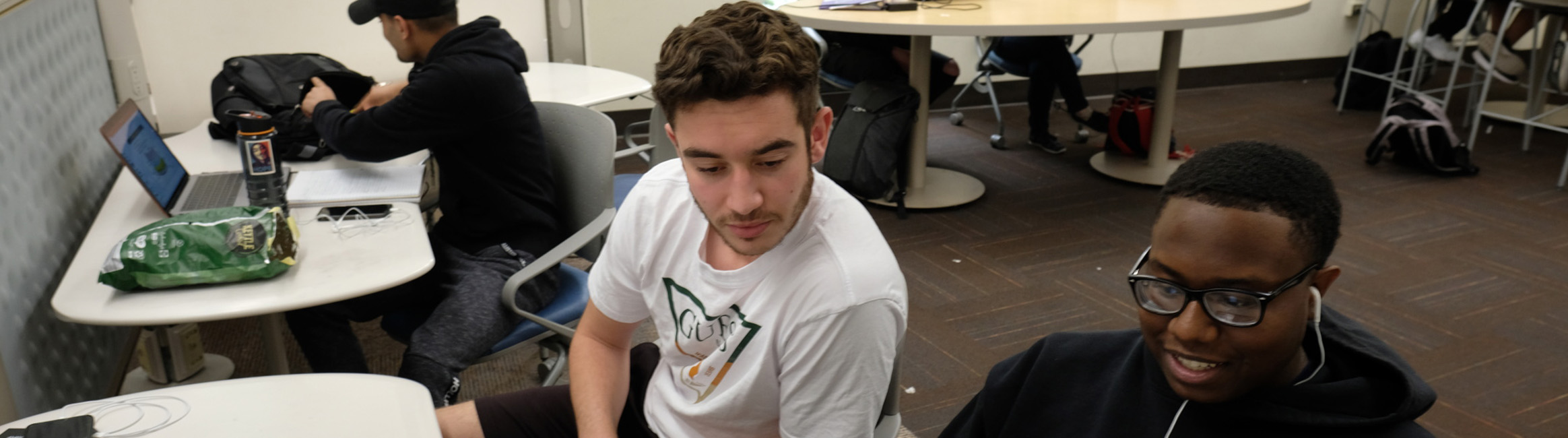 A photo of two students at a desk in Cabell on the second floor having a discussion.