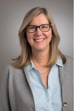 Headshot of a woman with glasses wearing a gray business suit