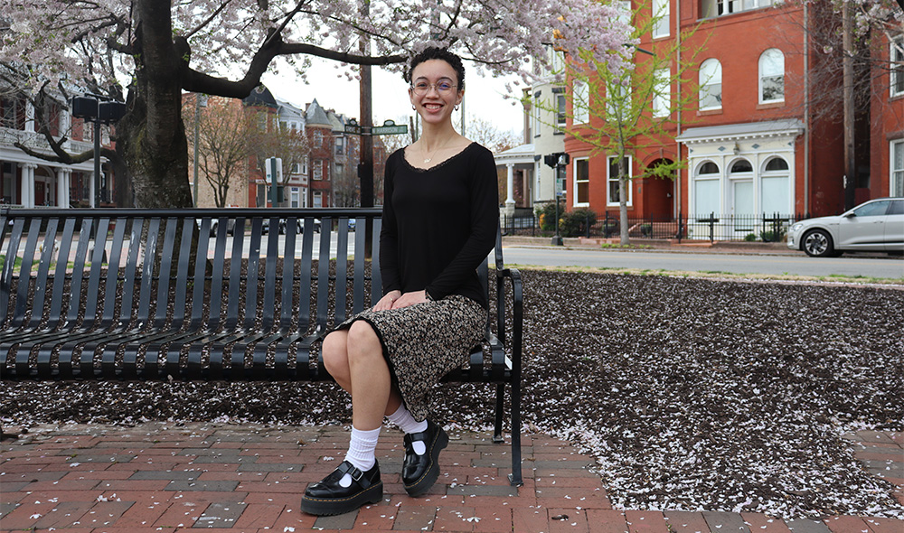 Lia New sitting on a bench on Monroe Park Campus.