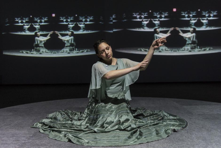 Woman in green dress kneels on floor.