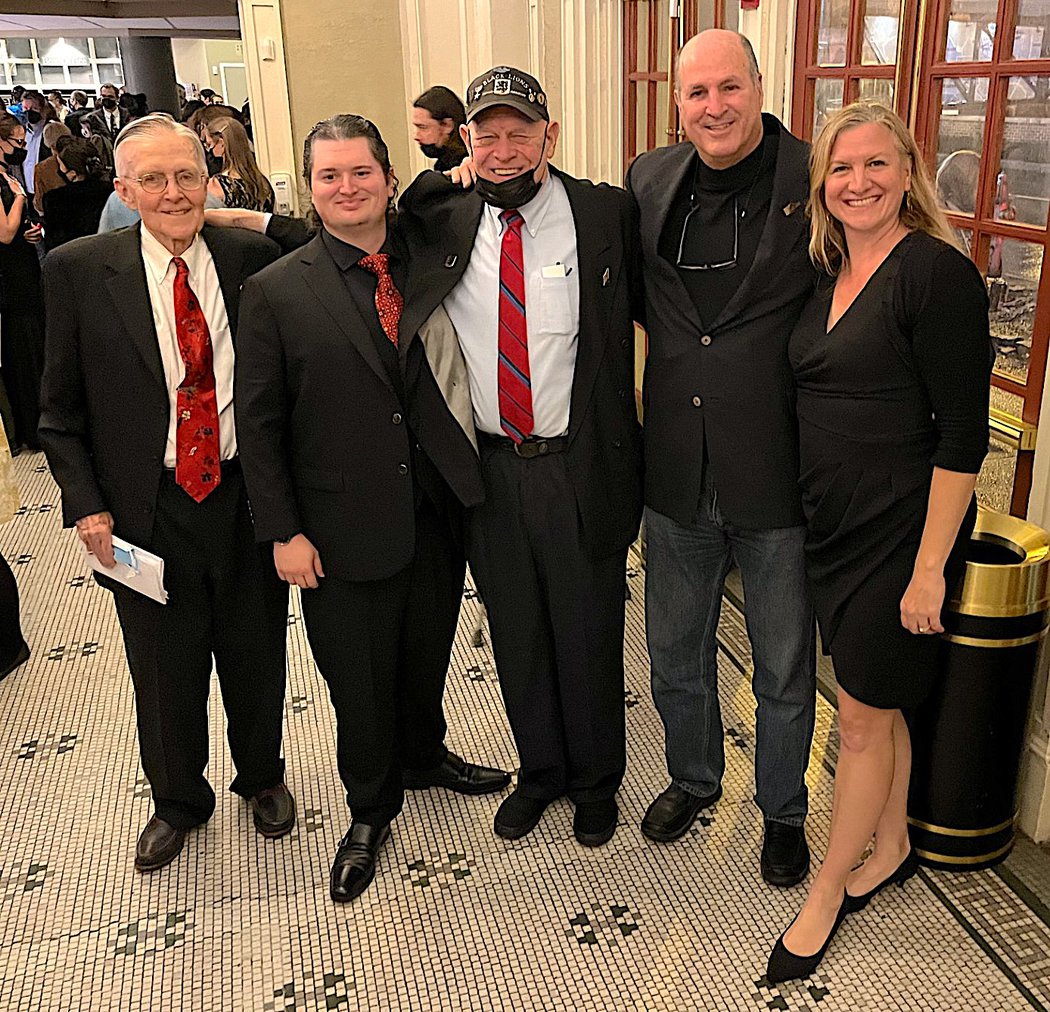 Five people dressed in formal wear posing together.