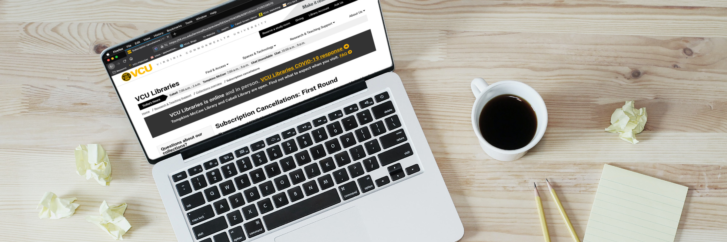 A laptop surronded by crumpled post-it notes and a cup of coffee displays the VCU Libraries page about the first round of Journal Cancellations.