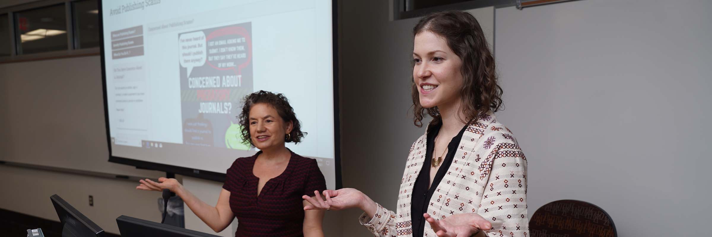 Hillary Miller and Erica Brody talking in front of a screen.