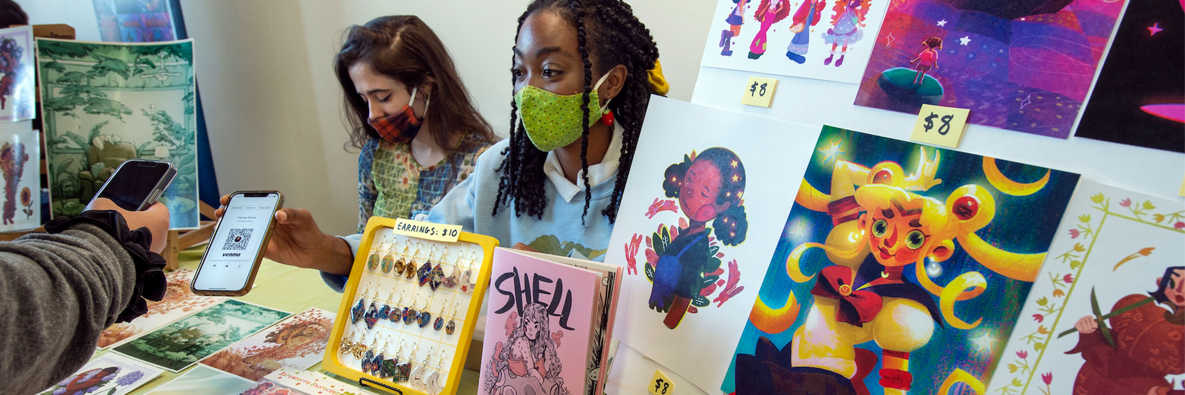 VCU graduates Camryn Simms (right) and Lillian Trenton display and sell their artwork.