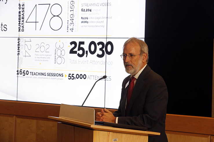 John Ulmschneider standing at a podium in front of a screen.