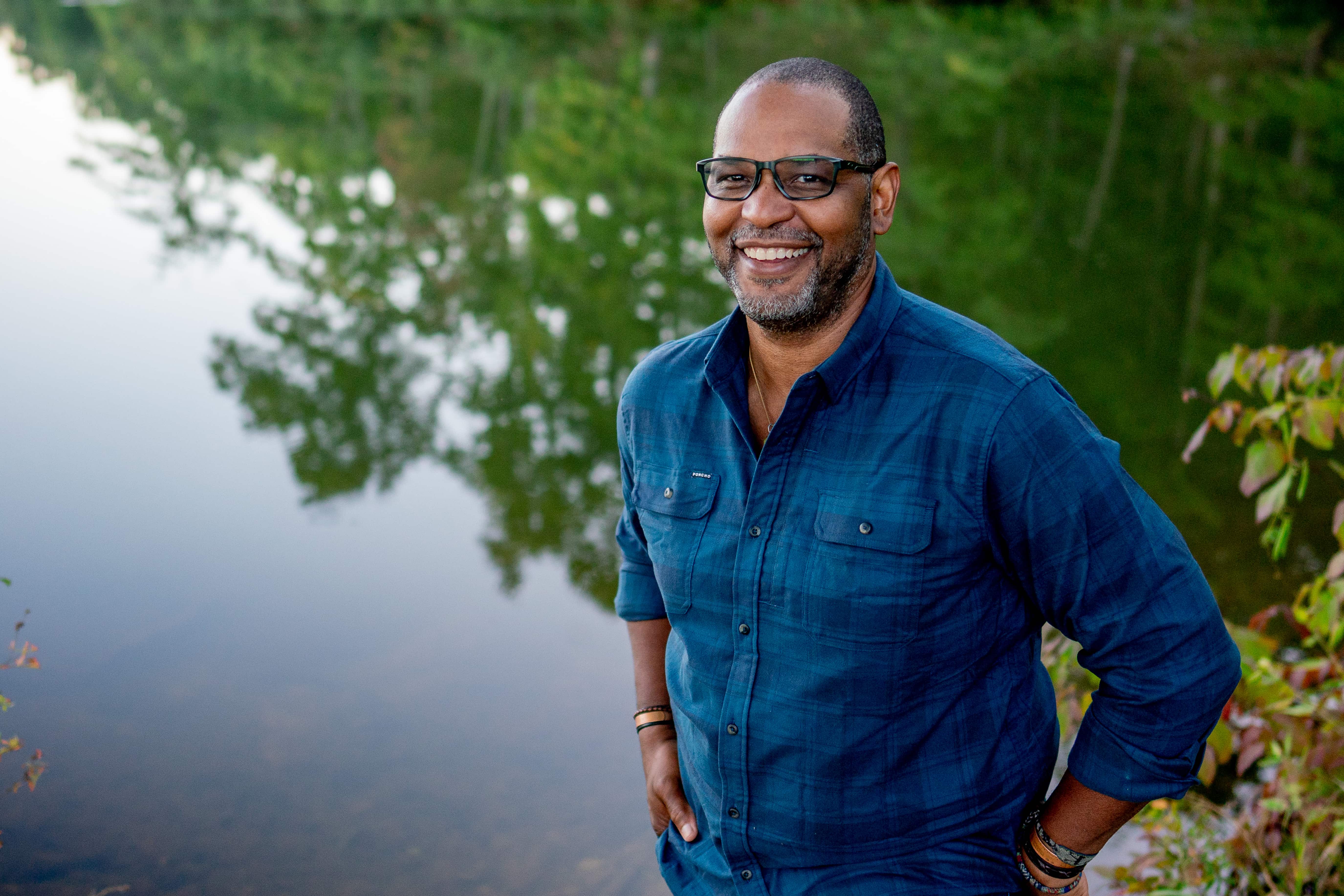 A man smiling, standing under a tree