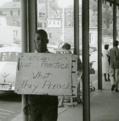 Protester carrying practice what you preach sign